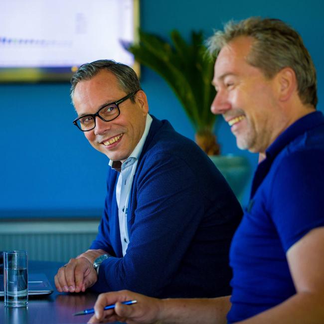 Tom van Asten en Maik Wilms lachen tijdens een meeting