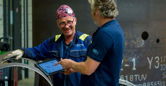 Colleagues discuss their work with a tablet in the Montair workshop