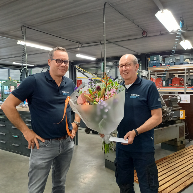 Tom van Asten feliciteert collega Huub van Berlo met zijn jubileum met bloemen